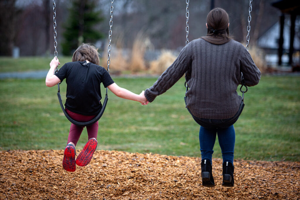 Parents are being held responsible for their kids’ crimes under new laws 1 A mother and her son hold hands on a swing set. This year, more state and local leaders are pushing to hold parents accountable for their children’s behavior, particularly when it involves serious criminal offenses. (Photo by Troy Bennett/Maine Morning Star)